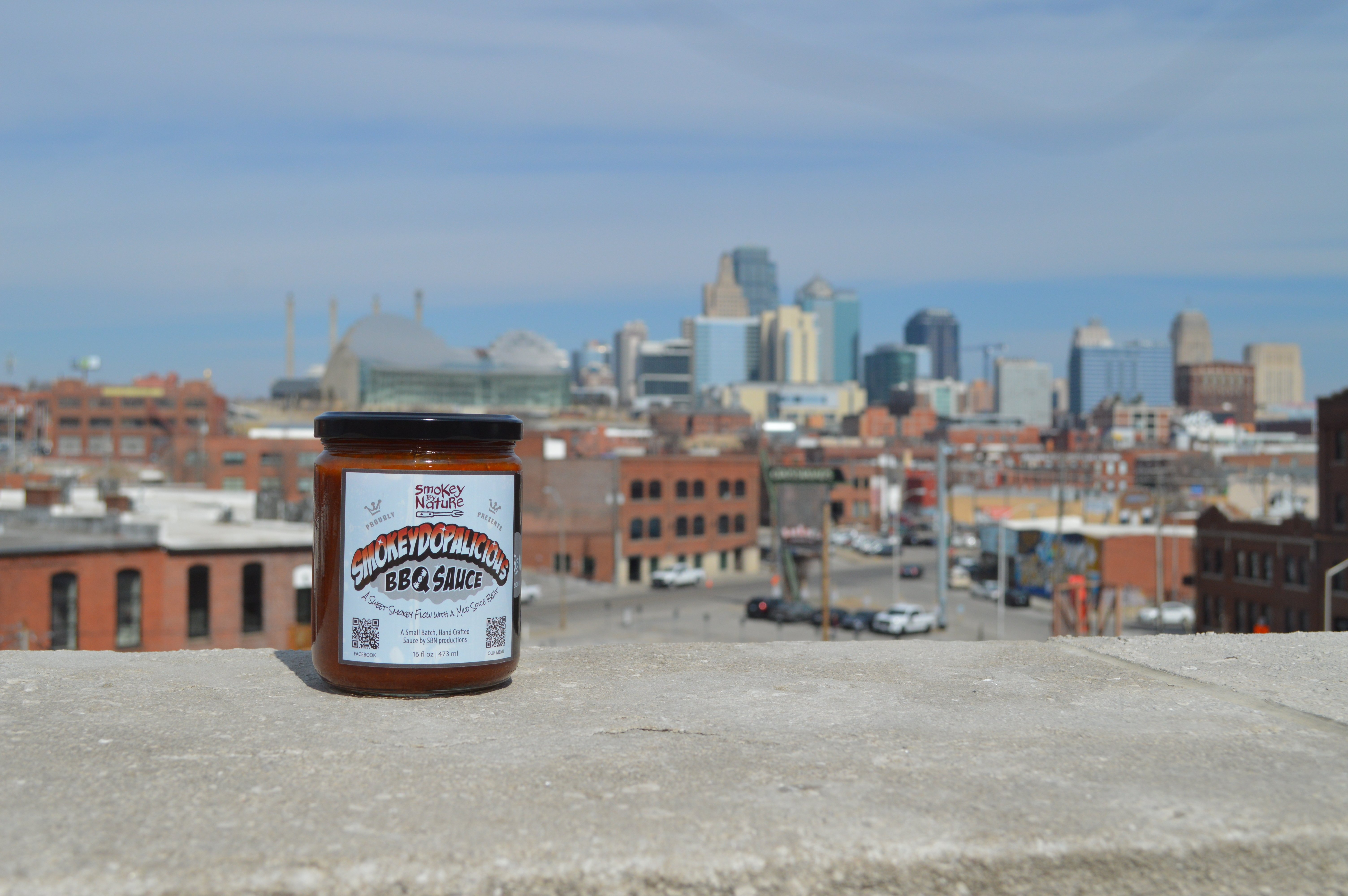 Jar of BBQ sauce with Kansas City skyline in background